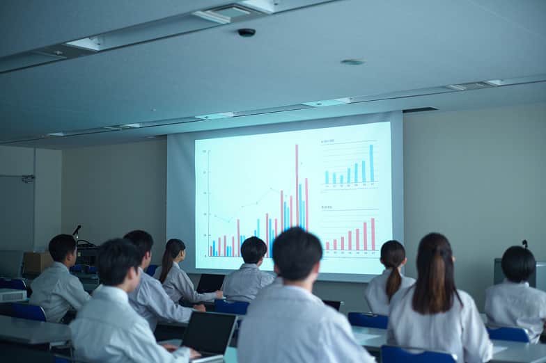 研修室で講義を受ける社員たちの後ろ姿