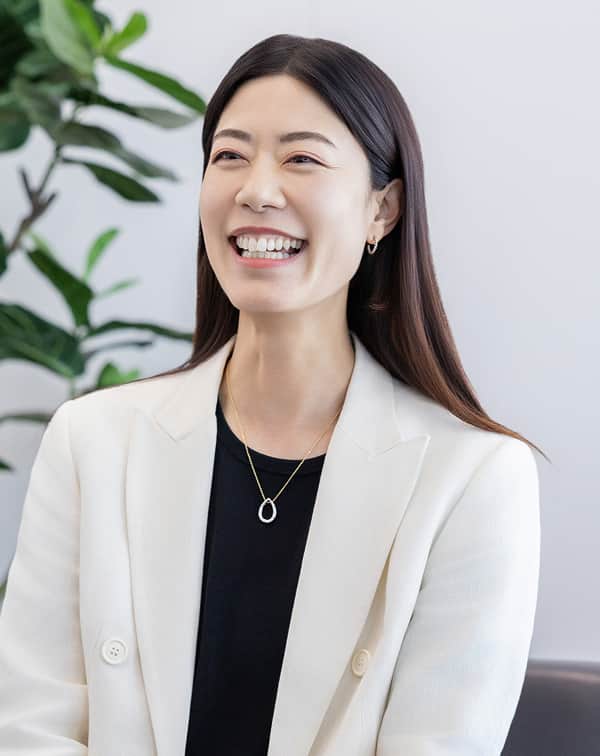 白いジャケットを着た女性社員が笑顔で話す様子